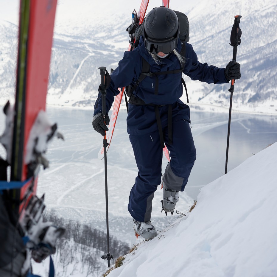 Eine Frau steigt mit Schneeschuhen einen Berg hinauf